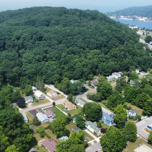 Overall:  an aerial view of the north end of elberta with the home visible at the bottom center along with the elberta dunes, lake michigan, betsie bay, and downtown frankfort across betsie bay.