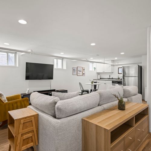 Basement living room upgraded with seating for all and a tv.