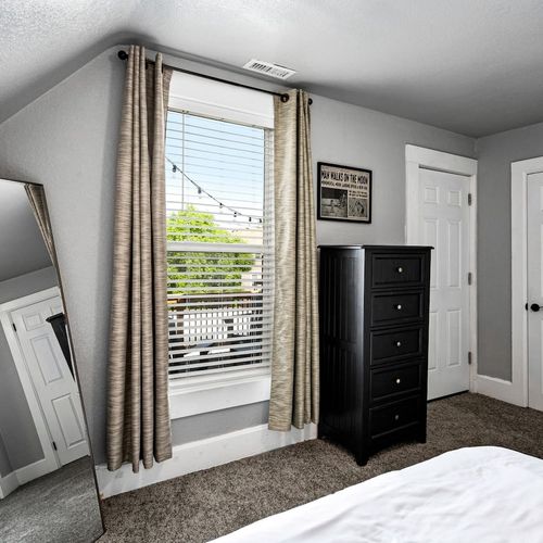 - bright window with string light views adds charm to this upstairs retreat
- tall black dresser offers plenty of storage and blends with neutral tones
- full length mirror and carpeted floors make getting ready easy and cozy