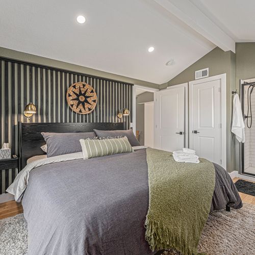 - earthy tones meet modern style in this restful retreat with soft linens and warm textures
- artistic wall paneling and rattan decor add flair and personality to your stay
- ensuite bathroom with walk in shower and rain style head for relaxing morni