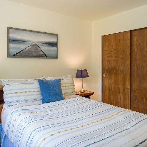 Guest bedroom with a large closet, luggage racks, and full bathroom in the hallway.