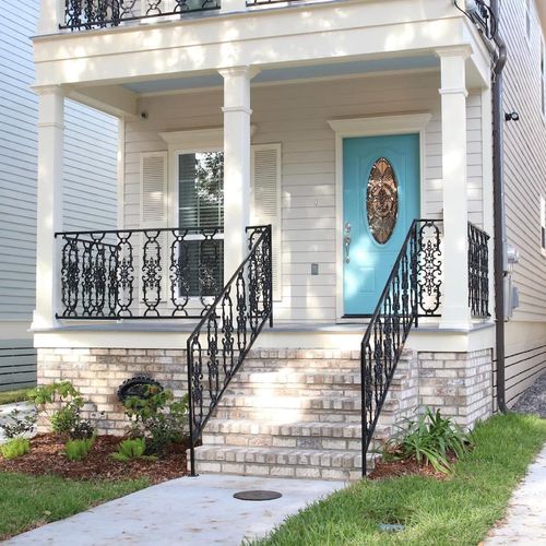 Charming front entrance w/ classic ironwork balcony & a welcoming teal door.
