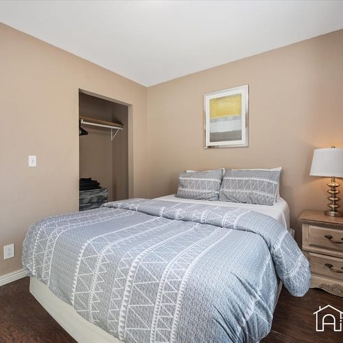 - clean and simple design with a soft gray comforter, framed artwork, and nightstand lighting
- closet space for storing luggage or hanging clothes during longer visits
- warm tones and cozy textures create a peaceful sleep environment