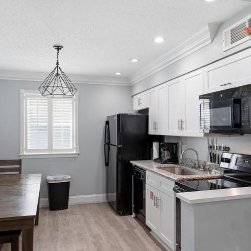 Sleek kitchen w/ black appliances — cook, dine & unwind in one space.