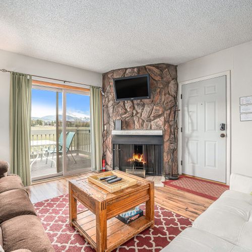Unwind in a comfy living room with fireplace, soft glow, and stunning skyline through big windows.