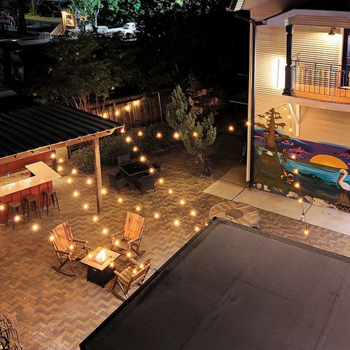 Charming night view of our patio with string lights, cozy fire pit, and bar area, perfect for unwinding after a day in the city.