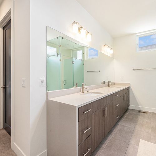 This neat bathroom is enhanced by a large mirror and a calming, spa-inspired feel.