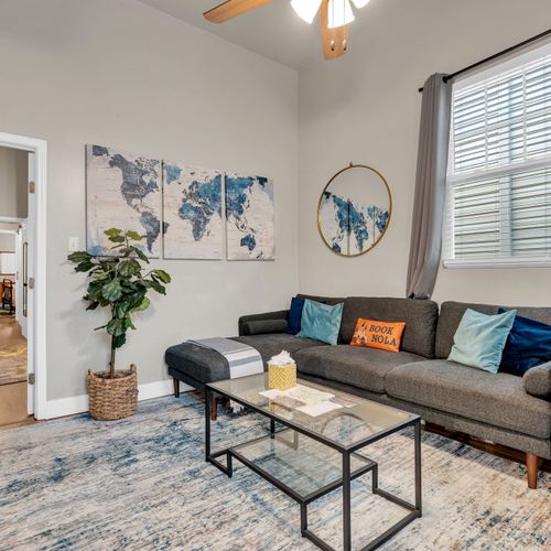 Bright living room w/ a cozy sofa, world map wall art & plenty of natural light.