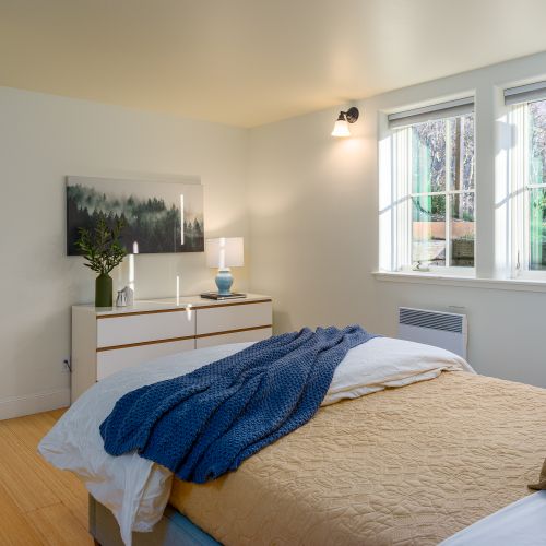Bright and airy bedroom corner featuring cozy textures and large windows that bring in natural light.