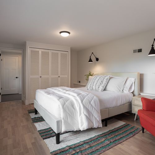 Downstairs Guest Bedroom with a reading chair, door to a private balcony, and full bathroom.