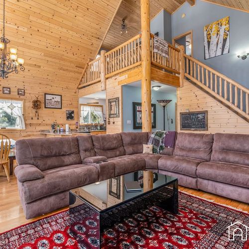 - plush l shaped sectional provides plenty of room for movie nights or group hangs
- cabin’s open layout includes soaring ceilings, wood beams, and upstairs loft views
- gather together under the antler chandelier in this warm & welcoming great room
