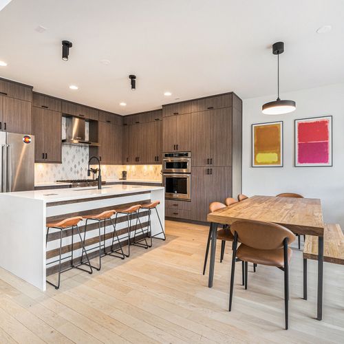 A modern kitchen-dining area with stainless steel, artistic touches, and soft, elegant lighting.