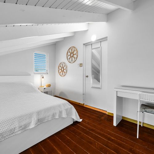 Cozy under the eaves. Sleep soundly in this peaceful space with soft lighting and beachy touches.