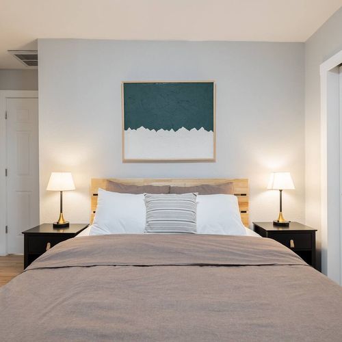 - relax in a welcoming bedroom styled with soft lighting and a sleek wood headboard
- dual nightstands and warm lamps create balance and bedside convenience
- minimalist wall art and neutral tones add a calm, restful atmosphere