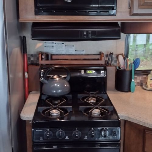Kitchen:  the home has a cute little kitchen with a refrigerator, sink, counter, stove, oven, and microwave. There is also a collection of cooking and dining utensils provided.