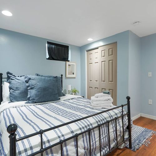 - cozy basement bedroom with striped bedding, plush pillows, and warm lighting
- soft blue walls, wood floors, and closet space make it functional and stylish
- perfect for winding down in comfort after a day of adventure or exploring