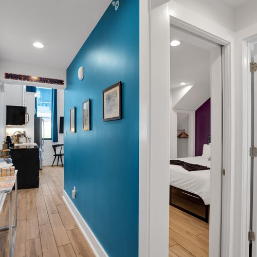 Teal hallway w/ vibrant accents connects rooms w/ bold, flowing energy.