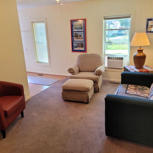 Living room:  features a loveseat, comfy chairs, live-streaming television with roku, and a ceiling fan.