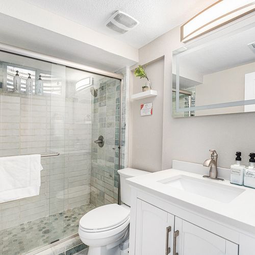 - unwind in a sparkling glass walk in shower with natural tile tones and built in storage
- crisp white vanity and stylish mirror lighting keep the space bright and modern
- thoughtful touches like mounted dispensers and soft towels enhance your stay
