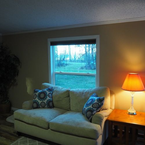 A nice view of the living room at dusk, with green lake visible through the living room window.
