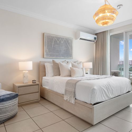 Relax in comfort on your plush, king-sized bed, featuring serene decor and ample light.