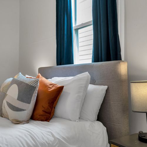 Bed dressed in layered pillows & warm tones for a snug, comfortable sleep.