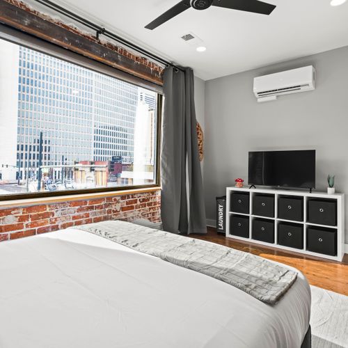 Queen bed with soft linens and blackout curtains.