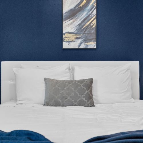 Relax and unwind in a cozy bed with a bold blue accent wall that adds a touch of elegance to your restful retreat.