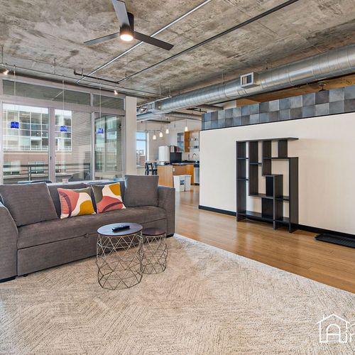 - hang out in this modern industrial style space with concrete ceilings and wood floors
- stylish couch with colorful pillows makes a bold and comfy statement
- open concept design connects the living area to kitchen and balcony