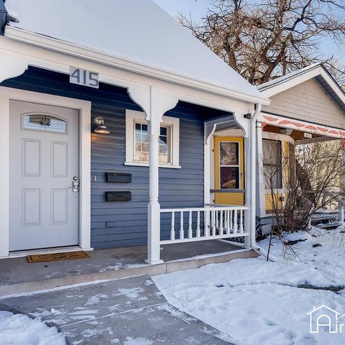 Charming front entry at 415 with a covered porch, fresh paint, and snowy path leading to the welcoming doorway.