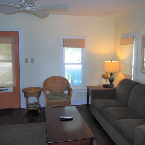 Living room: the apartment has a cozy living room with a sofa, chair, ceiling fan, and live streaming television.
