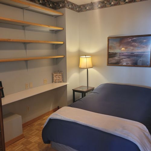 Bedroom #1 (main floor):  features a full-size bed, lots of shelving, a ceiling fan, and a dresser.