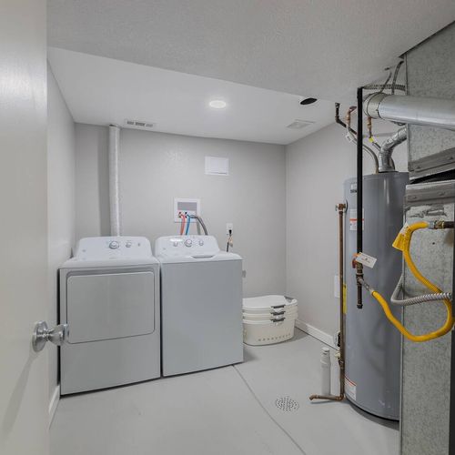 - utility room with washer, dryer, laundry supplies, and mechanical access in one place
- clean concrete floors and bright lighting keep the space organized and accessible
- practical feature for long stays or traveling with family