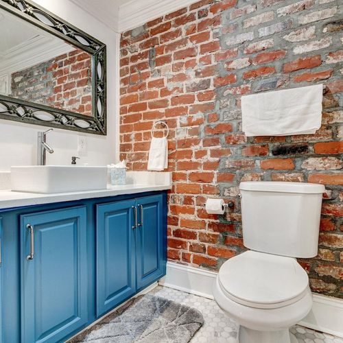 Full bathroom w/ tub & modern blue cabinetry.