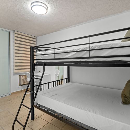 Enjoy the simple comforts of this bedroom, equipped with clean, crisp bedding on bunk beds and easy access to the study area.