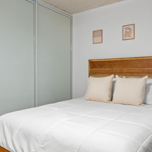 Enjoy the comfort and simplicity of this well-appointed bedroom, complete with a stylish wooden bed frame and subtle art accents.