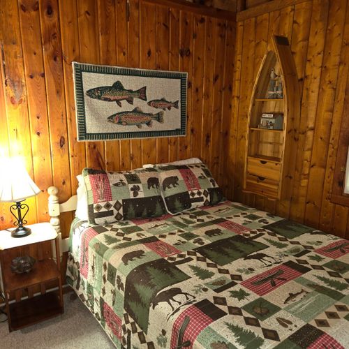 Bedroom #2:  this bedroom is at the front of the cabin from off the living room and features a full-size bed, nightstand, lamp, dresser, mirror, and closet.