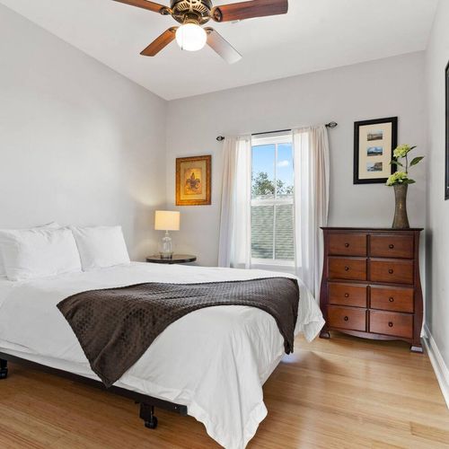 Cozy bedroom w/ a bed, warm wood dresser & soft natural light.