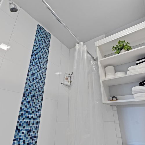 Second floor full bathroom w/ tiled shower & open shelving.