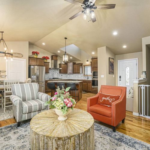 A bright, airy living room connects to the kitchen, showcasing stunning lighting features and natural wooden decor.