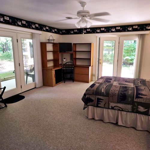 Bedroom #1:  the cabin has a large primary bedroom with a queen-size bed, desk, comfy chair, ceiling fan, dresser, and closet.