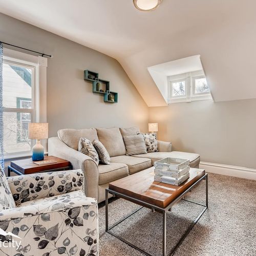 - relax in a cozy upstairs lounge with plush carpeting and soft beige sectional sofa
- floral armchair and wooden coffee table complete the room’s inviting setup
- dormer windows and geometric wall art add light and artistic flair