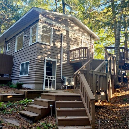 EXTERIOR:  The side of the cottage, highlighting the stairs up to the entrance on the second floor.
