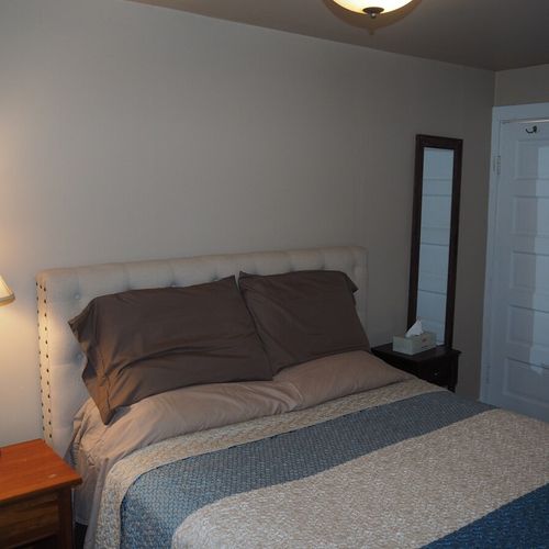 Bedroom #1:  features a queen-size bed, mirror, nightstands, lamps, dresser, chair, and television.