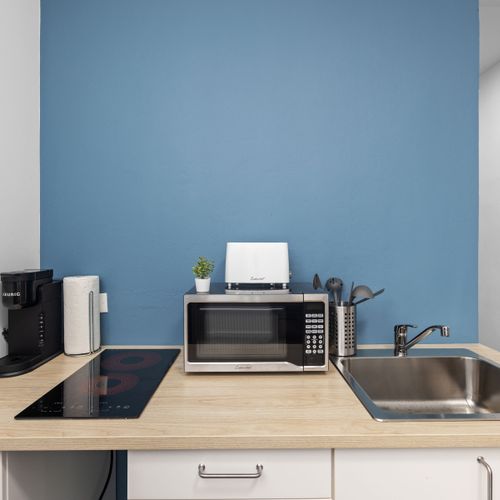 Modern kitchenette with vibrant blue accents and sleek white walls.