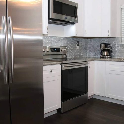 Sleek kitchen w/ stainless steel appliances & classic tile backsplash.