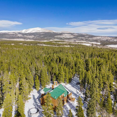 Secluded log cabin tucked in a snowy forest with sweeping views of snow capped peaks and endless pine trees.