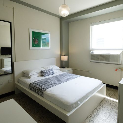 Cozy and contemporary. This inviting bedroom offers a comfortable bed with modern bedding, providing a bright and relaxing space perfect for your stay.