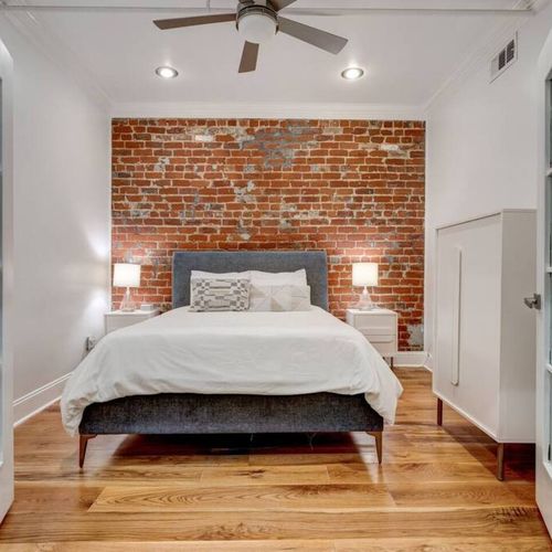 Airy bedroom w/ a queen bed nestled against charming exposed brick walls.