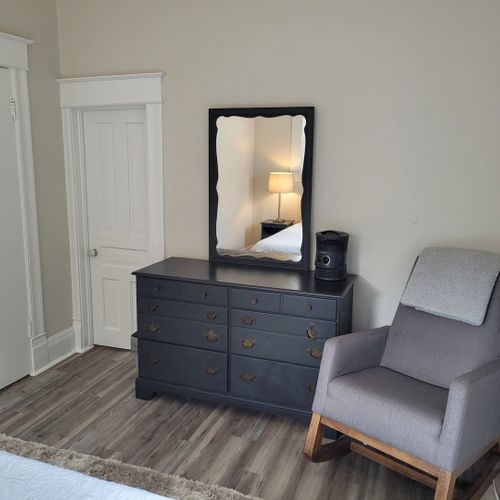 Bedroom #1 (main floor):  features a queen-size bed, ceiling fan, window a/c unit, nightstands, lamps, chair, dresser, mirror, and a closet.